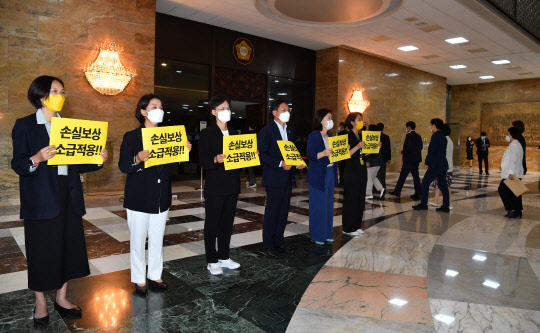 정의당 의원들이 1일 국회 본회의장 앞에서 코로나19 손실보상 소급적용을 촉구하고 있다. 연합뉴스